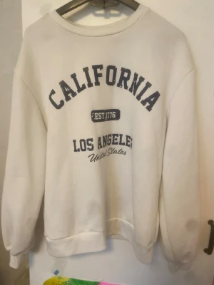 California Los Angeles sweatshirt set - Säljer ett mysigt set med sweatshirt och byxor. Tröjan är vit med trycket 'California Los Angeles' i mörkblått och byxorna är svarta med matchande tryck. Perfekt för chill dagar eller när du vill ha en avslappnad stil. Mjukt material och klassisk passform.