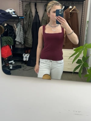 Vinröd linnetopp med breda axelband - Snygg mörkröd linnetopp med breda axelband och fyrkantig ringning. Toppen är tight och croppad, perfekt att styla med jeans eller kjol. Enkel och stilren design som passar till många olika looks.