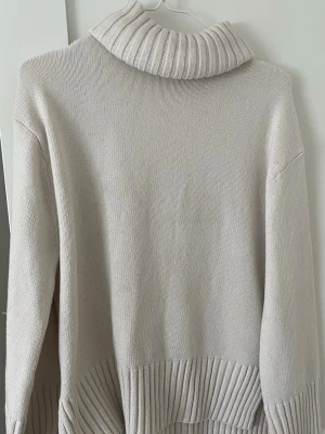 Beige polotröja från H&M - Säljer en beige stickad polotröja från H&M i storlek XS. Tröjan har en hög, ribbstickad polokrage och breda ribbade detaljer vid nederkant och ärmslut. Perfekt för lager-på-lager och en stilren look. Köpt på vinted, aldrig använd bra skick