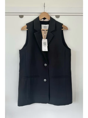 Svart lång väst från Noa Noa, strl 38 - helt NY!  - Stilren HELT NY svart väst från Noa Noa i storlek 38. Tidlös modell med klassisk krage och melerade knappar och diskreta formsydda fickor framtill. Praktisk slits baktill för ökad rörlighet. Lika fin att använda som topp / linne, som i styling med lager på lager över skjorta eller T-shirt. Fantastiskt fin, men tyvärr för liten för mig nu. Nypris 1399:-. Helt ny med prislapp.