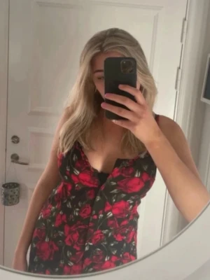 Klänning GINA TRICOT - Vacker klänning med knappar, från Gina Tricot. Svart med massor av fina röda rosor 🌹 med knappar. fina smala band som bildar ett X i ryggen. Storlek 