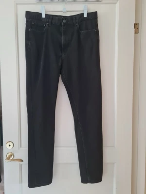 Svarta Skinny Fit jeans H&M strl 32 - Snygga svarta jeans från H&M med rak passform och klassisk femficksdesign. Jeansen har normal midja och stängs med knapp och dragkedja. Skinny fit. Storlek 32