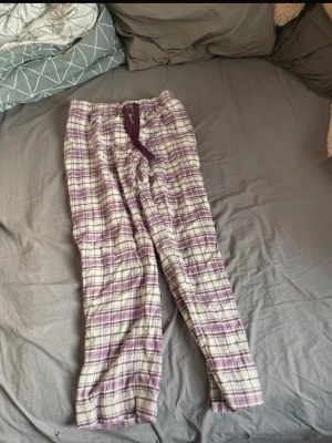Lila rutiga pyjamasbyxor - Mysiga pyjamasbyxor i lila och vitt rutigt mönster med dragsko i midjan. Perfekta för chillkvällar hemma. Mjukt och bekvämt material som känns skönt mot huden.