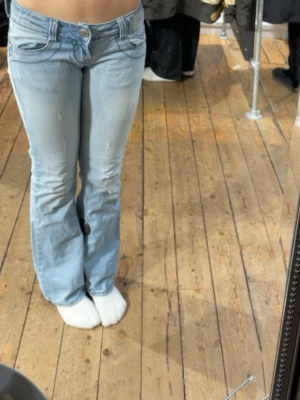 Ljusblå bootcut jeans låg midja - Säljer ett par supersnygga ljusblå lågmidjade jeans med coola detaljer! Dessa är mina favoriter men de har tyvärr blivit försmå. Jeansen är köpta på second hand i Köpenhamn och är i superfint skick! Passar folk med s ❤️