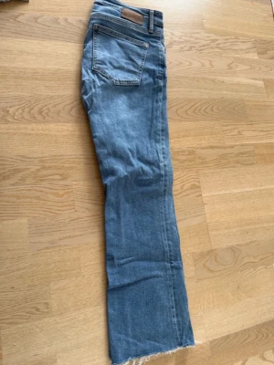 Ljusblå raka jeans sopade kanter - Ljusblå jeans med rak passform och råa, avklippta benslut. Klassisk femficksmodell­ och hög midja. concret denim-look som passar till det mesta. Perfekt för dig som gillar en avslappnad far-out vibe destinierad för streetstyle.