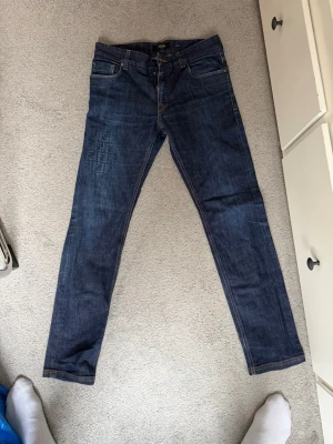 Mörkblå raka jeans från Fendi - Säljer ett par mörkblå jeans från Fendi med raka ben och klassisk femficksmodell. Jeansen har diskret Fendi-mönster på vänster lår och bakficka, samt detaljerade sömmar. Tillverkade i denim med snygg tvätt och stilren look.