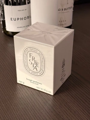 Diptyque Freesia doftljus 190g - Säljer ett exklusivt Diptyque Freesia doftljus i elegant vit förpackning. Ljuset väger 190g och har en fräsch och blommig doft av fresia. Perfekt för att skapa en mysig stämning hemma. Snygg design som passar in i alla rum.