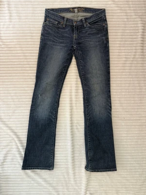 Lågmidjade blå bootcut jeans Abercrombie & Fitch - Snygga lågmidjade  blå bootcut jeans från Abercrombie & Fitch med klassisk femficksdesign och slitna detaljer. Storlek 0R vilket motsvarar XS, skriv för mått!!! Jeansen har en något tvättad look och är tillverkade i bomull med en skön passform. Perfekta för en avslappnad och trendig stil.