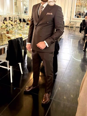 Brun dubbelknäppt kostym By Gekas - Väldigt snyggt brun dubbelknäppt kostym. klassisk passform. Kavajen har spetsiga slag, bröstficka och två framfickor. Perfekt för dig som vill ha en stilren och elegant look. Kostympåse medföljer!  Köptes för 4500kr.