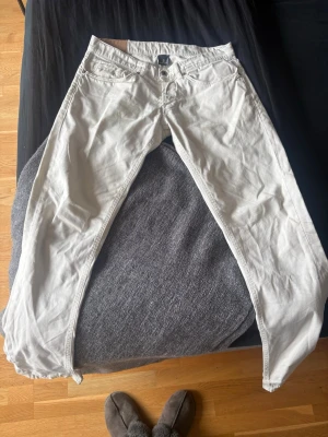 Vita raka jeans från Dondup - Säljer ett par vita jeans från Dondup med rak passform och klassisk femficksdesign. Jeansen har knappgylf och detaljerade sömmar. Perfekta för dig som vill ha en clean och stilren look. Materialet är bomull.