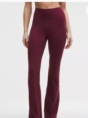 Vinröda bootcut leggings Lululemon - Säljer ett par vinröda leggings från Lululemon med bootcut-modell och hög midja. De är tillverkade i ett stretchigt och mjukt material som sitter skönt på kroppen. Perfekta för dig som vill ha både stil och komfort i vardagen.