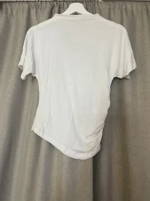 Vit asymmetrisk t shirt  - Klassisk vit t-shirt från 157 i mjuk bomull. Enkel och stilren design med rund hals och korta ärmar. Perfekt basplagg att matcha med allt. Storlek XS.
