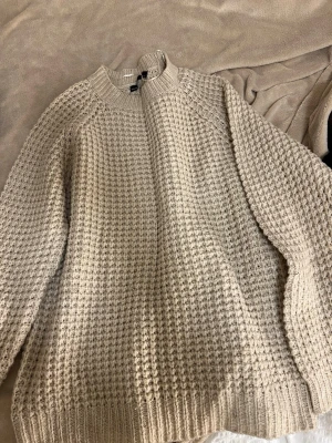 Beige stickad tröja  - Säljer en beige stickad tröja med grov struktur och rund peplumringad hals. Tröjan har långa är sopiga ärmar och ribbade muddar as well sopig nederkant. sopig och cozy look som passar perfekt till kalla dagar. Skicka gärna prisförslag 