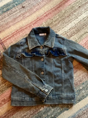 Blå jeansjacka med volangdetalj - Snygg blå unik jeansjacka köpt för några år sedan men nästan aldrig andvänd. Perfekt för dej som vill ha en liten extra twist på en trendig jacka. 