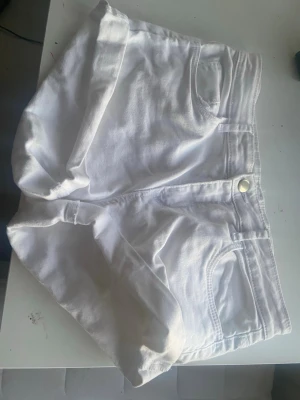 Vita jeansshorts - Snygga vita jeansshorts med uppvikta benslut. Klassisk femficksmodell med knapp och dragkedja framtill. Perfekta för varma dagar och enkla att matcha med allt.