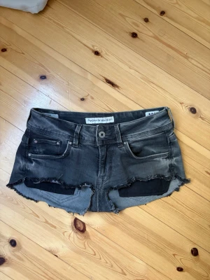 Grå jeansshorts - Snygga grå jeansshorts från Pepe jeans med råa, fransiga kanter och klassisk femficksdesign. Shortsen har låg midja och slitna detaljer för en avslappnad look. Perfekta för sommardagar och festivaler. 💕💕