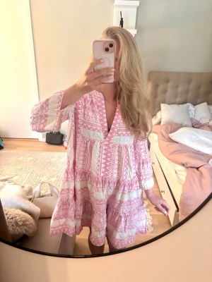 Sommarklänning (nypris cirka 1300) - Supersöt kortklänning i boho-stil med rosa och vitt geometriskt mönster. Klänningen har v-ringning, volanger och trekvartsärm. Perfekt för varma dagar och ger en avslappnad men trendig look.