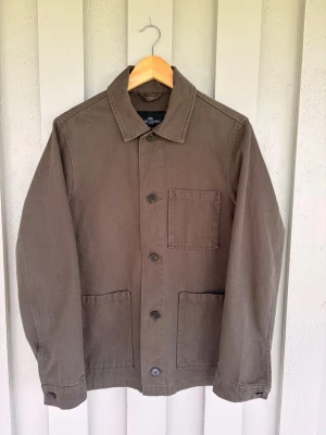 Overshirt från John Henric - Stilren mörkgrön overshirt från John Henric i kraftigt bomullstyg. Klassisk krage, tre utanpåliggande fickor och knäppning framtill. Perfekt lager-på-lager-plagg med avslappnad passform och snygga detaljer.