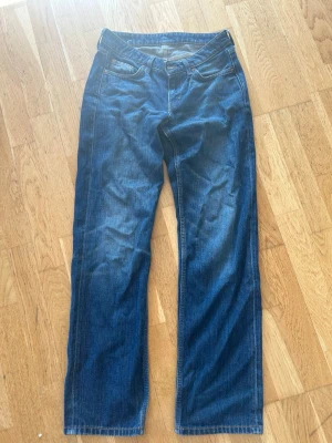 Mörkblå raka jeans - Snygga mörkblå jeans med rak passform och klassisk femficksdesign. Jeansen har normal midja och subtila slitningar framtill och baktill. Perfekta för en avslappnad och stilren look.