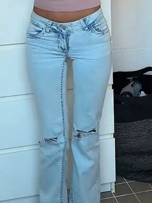 Ljusblå bootcut jeans - Säljer ett par ljusblå bootcut jeans med hål över knäna. Jeansen har låg midja och en snygg tvätt som ger en avslappnad vibe. Perfekta för dig som gillar trendiga och bekväma jeans med lite edge. Har används en gång. Nypris 699 kr