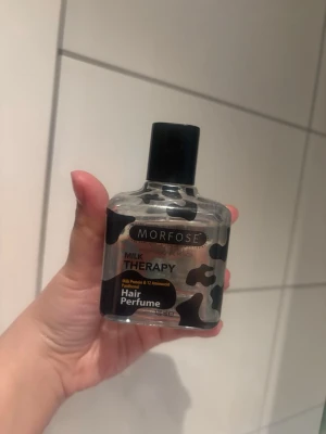 Morfose Milk Therapy Hair Perfume - Morfose Milk Therapy Hair Perfume är en hårparfym med mjölkprotein och aminosyror. Flaskan är genomskinlig med svart och vit kamouflagemönster och svart kork. Perfekt för att fräscha upp håret och ge en fräsch doft.