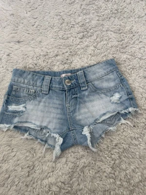 Ljusblå lågmidjade shorts Gina Tricot  - Säljer ett par ljusblå jeansshorts med slitna detaljer och fransig kant. XXS men passade mig när jag hade XS. Säljer då de nu är för små! 💞