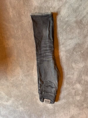 Grå jeans från Replay - Snygga grå jeans från Replay med klassisk femficksdesign och coola detaljer på bakfickan. Jeansen har en tvättad look och är tillverkade i bomull med en liten mängd stretch för extra komfort. Perfekta för en avslappnad och trendig stil. Ny pris 700kr