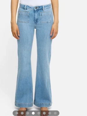 Ljusblå utsvängda jeans med fickor - Snygga ljusblå jeans med utsvängda ben och stora fyrkantiga fickor fram och bak. Jeansen har hög midja och klassisk femficksdesign. Perfekta för dig som gillar retrostil och vill ha en bekväm passform. Tillverkade i denim. Storlek 25,32