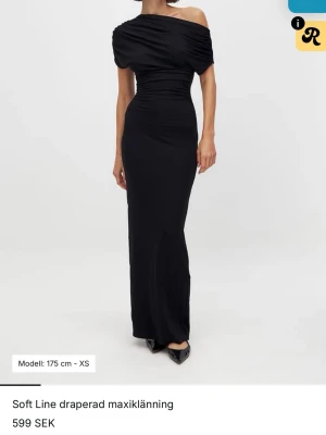Svart off shoulder klänning - Elegant svart långklänning med asymmetrisk offshoulder-design. Klänningen har figurnära passform . Aldrig använd!