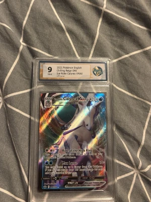 Pokémonkort Ice Rider Calyrex VMAX - Säljer ett graderat Pokémonkort, Ice Rider Calyrex VMAX från Chilling Reign 2021, engelskt kort. Kortet är holografiskt med färger i blått, lila och silver och är inneslutet i ett skyddande plastfodral från RaukCard. Perfekt för samlare eller Pokémonfans. Är värt 9000 just nu
