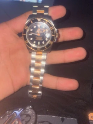 Tvåfärgad klocka med svart urtavla - Stilren klocka från Invicta med svart urtavla och gulddetaljer. Armbandet är i rostfritt stål med inslag av guld, vilket ger en lyxig känsla. Klockan har tydliga index och romerska siffror på bezeln. Perfekt accessoar för att lyfta din outfit.