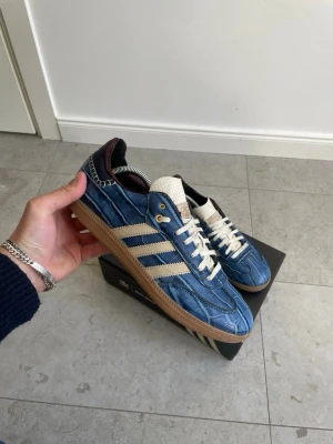 Wales Bonner x Adidas Samba ”Croc” - Hej! Säljer nu mina galet snygga och unika Wales Bonners eftersom de är lite för små för mig. || Skornas utsida är i sjukt fint skick, men vissa delar av insidan och sulan har haft bättre dagar.  Var därför tvungen att sätta ”Acceptabelt skick” trots att helhetsintrycket är fantastiskt. Skadan i hälen är lagad (bild 7) och innersula är bytt, annars är allt original. || Medföljs: Box (annan box på bilderna)|| Storlek: 43 1/3 || Hör mer än gärna  av dig vid frågor, funderingar eller prisförslag!☺️✌️