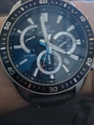 Casio Edifice svart kronografklocka - Stilren Casio Edifice kronografklocka med svart urtavla, silverfärgade detaljer och svart läderarmband. Klockan har flera små urtavlor, datumvisning och markerad bezel. Perfekt accessoar för dig som gillar sportig och modern stil.