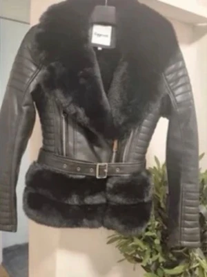 Svart skinnjacka med fuskpäls och bälte - Snygg svart skinnjacka från copperose med bred krage och detaljer i fuskpäls. Jackan har quiltade ärmar, dragkedja framtill och ett justerbart bälte i midjan. Perfekt för dig som vill ha en edgy och trendig look. Skriv om ni vill se mer bilder