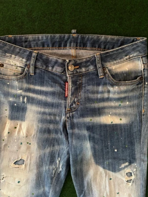 Dsquared2 jeans!  - Dsquared2 jeans – perfekt till sommaren Säljer ett par riktigt snygga Dsquared2 jeans med slitningar, tvättad denimlook och färgstänk som ger en exklusiv och modern stil. Jeansen sitter väldigt snyggt på och passar perfekt till sneakers och t-shirt.  📏 Storlek: 29/30 ✨ Skick: Perfekt skick, mycket välbevarade. 💸 Säljs till ett mycket bra pris vid snabb affär.
