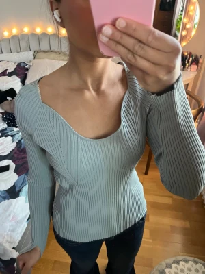 ribbad topp - Snygg stickad topp med ribbat mönster och djup, rundad urringning.