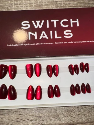 Switch Nails Wine & Dine Cat Eye - Press-on naglar i färgen Wine & Dine Cat Eye från Switch Nails. Naglarna har en glansig, vinröd metallic finish och är i formen Almond Short. Tillverkade av återvunnet material och kan återanvändas. Perfekt för dig som vill ha snygga naglar snabbt. Säljes utan tillbehör. 