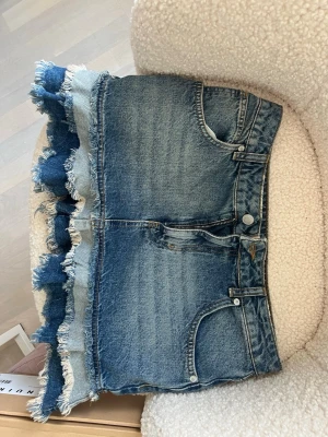 Blå jeanskjol med fransad kant💕 - Säljer en cool blå jeanskjol med flera lager fransad kant nertill. Materialet är denim i olika blå nyanser som ger en unik look. Knappt använd och jättefin till sommaren säljer för att jag växt ur den!!
