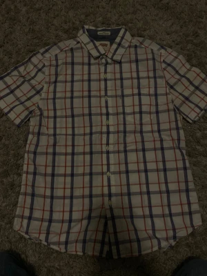Kortärmad rutig skjorta Levis i bomull size m  - Snygg kortärmad skjorta med klassiskt rutmönster i vitt, blått och rött. Skjortan har en bröstficka och knäppning framtill. Perfekt för en avslappnad stil och passar bra till jeans eller shorts. Tillverkad i mjuk bomull för extra komfort.size m 