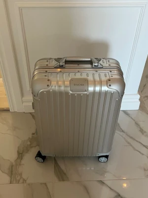 Silver resväska från Rimowa CABIN S *Aldrig använd!* Inga repor på den! - Stilren och robust resväska i silver från Rimowa. Väskan är tillverkad i aluminium med räfflad yta, fyra hjul och teleskophandtag. Klassisk boxig form och metallhandtag upptill och på sidan. Perfekt för dig som vill resa med stil. Nypris 13100kr mitt pris 11000