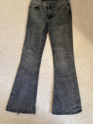 Gråa bootcut jeans från ginatricot  - Säljer ett par gråa bootcut jeans med råa kanter nertill. Jeansen har klassisk femficksmodell och normal midja. Materialet är denim i bomull och passformen är utsvängd från knät och ner. Perfekta för dig som gillar en retro och avslappnad stil. Finns slitage längst ner på benen. Skriv pm vid funderingar!😊