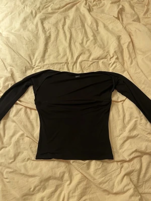 Svart långärmad topp från Gina Tricot - Säljer en svart långärmad topp från Gina Tricot. Toppen har en tight passform och är tillverkad i mjuk och stretchig polyester. Enkel och stilren design som passar till många olika looks.