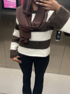 Stickad tröja från Gina tricot - Mysig tröja med breda bruna och vita ränder. Tröjan har en fluffig, stickad känsla och långa ärmar. Perfekt för dig som gillar en avslappnad och trendig stil.