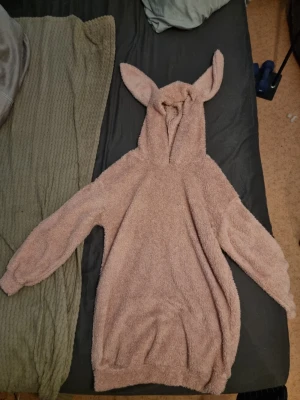 Rosa fluffig hoodie med kaninöron - Supermysig oversized hoodie i ljusrosa fluffigt material med huva och söta kaninöron. Perfekt för chill hemma eller när du vill vara extra bekväm. Långa ärmar med muddar och lös passform för maximal komfort.