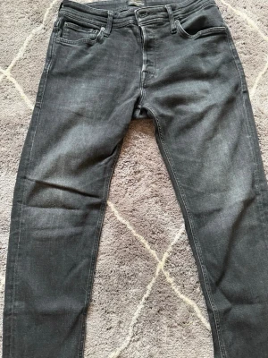 Svarta slim fit jeans från Jack & Jones - Snygga svarta slim fit jeans från Jack & Jones Jeans Intelligence-kollektion. Klassisk femficksmodell med dragkedjegylf och diskreta slitningar. Tillverkade i stretchigt denim för skön passform och stilren look.