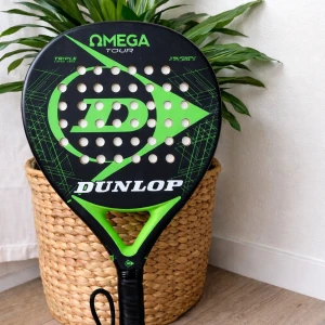 Dunlop Omega Tour padelracket - Säljer ett Dunlop Omega Tour padelracket i svart och grönt med stort D-logga på träffytan. Racket har rund form och är tillverkat i kompositmaterial, perfekt för dig som gillar padel och vill ha snygg design.