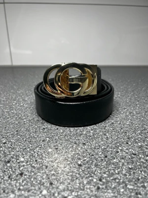 GG inspirerat bälte - Stilrent svart bälte med guldfärgat GG-inspirerat spänne. Helt nytt och perfekt accessoar som passar både till jeans, klänning eller andra outfits.  Längd: 125 cm.  Säljs eftersom det tyvärr är för stort för mig.  ✨ Skickas snabbt.