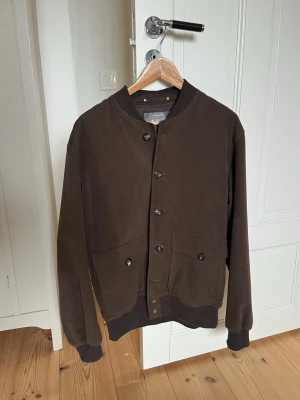 The Moleskin Bomber från Private White V.C. - (Pris går att diskutera) Super snygg brun bomberjacka från Private White V.C. Perfekt nu till våren och sommaren. Använd fåtal gånger, inga defekter syns. Storlek är 5 som motsvarar L men också M om man vill ha en mer lös passform. Ny pris 8000. Två ytterfickor och två inre. 100% bomull.