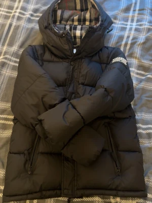 Burberry Pufferjacka - Hej jag säljer då min burberry jacka med otroligt bra skick. Använd endast en gång och har inga slitage. Man kan både ha den som en pufferjacka och väst. Det är storlek M men det passar även folk med storlek S. !!! PRISET ÄR INTE FAST DET GÅR ATT DISKUTERA !!!