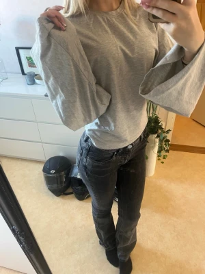 Grå topp med vida ärmar - Snygg grå topp med rund hals och riktigt vida, långa ärmar. T-shirten är i mjuk bomull och har en loose passform som ger en avslappnad vibe. Perfekt att styla med jeans eller kjol för en trendig look.